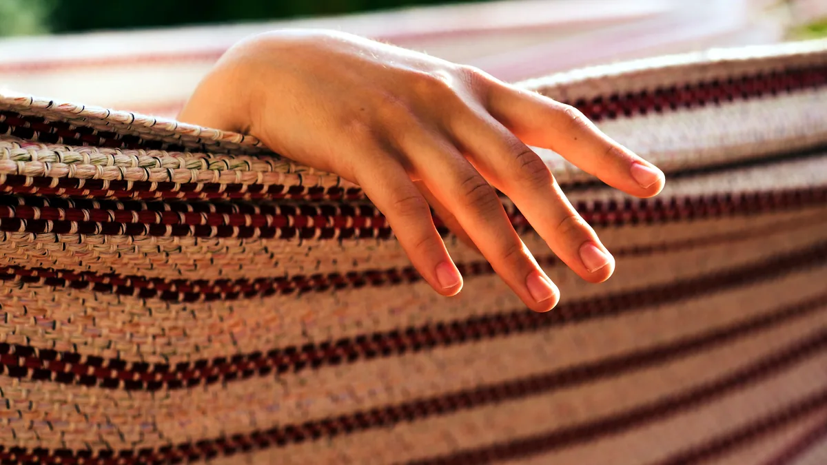 Fingers tracing the raised texture of a handwoven wool sample.