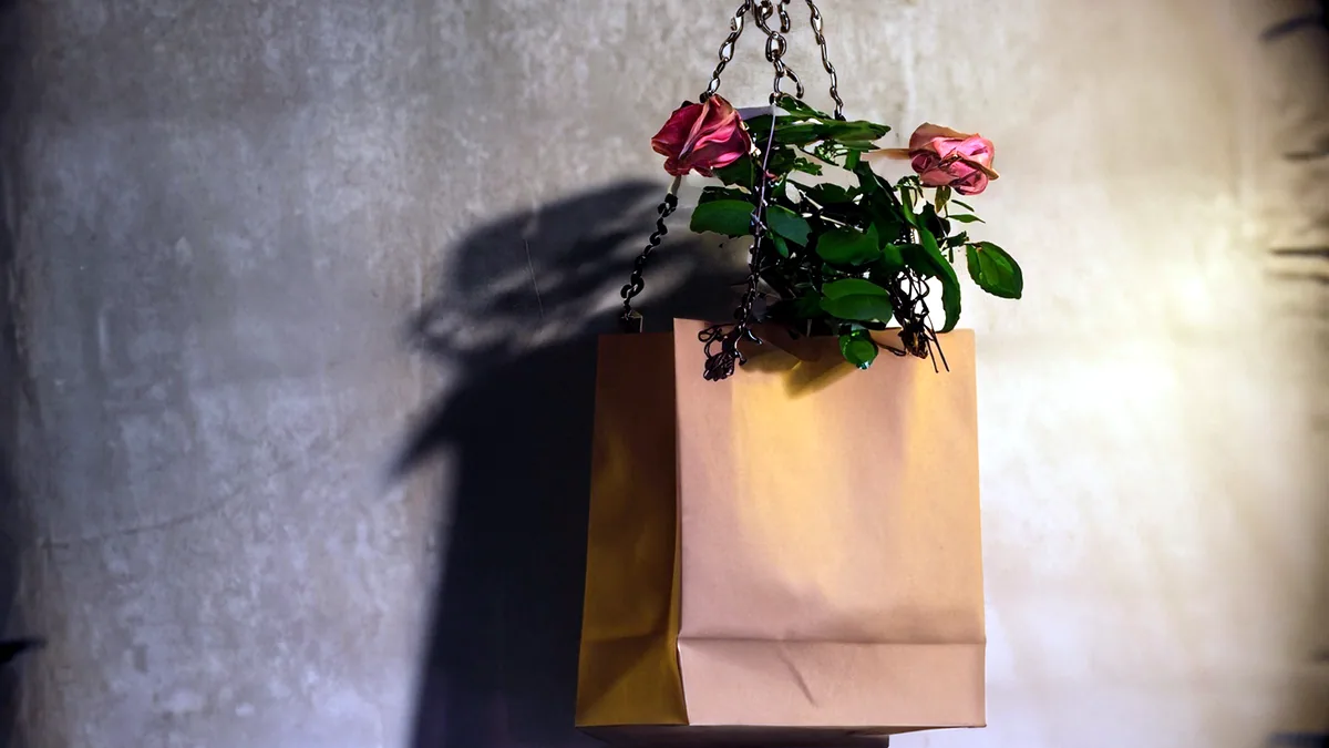 A kraft-paper flower delivery bag resting on a front doorstep.