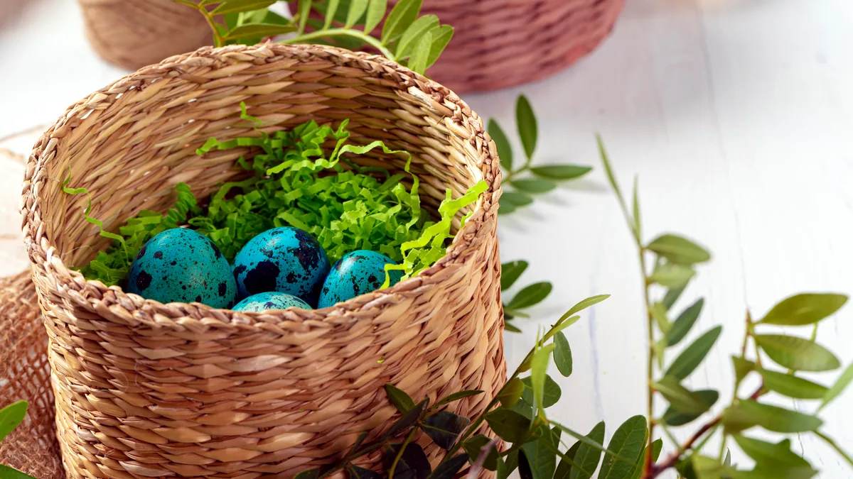 A woven basket holding hand-painted easter eggs in pastel colors.