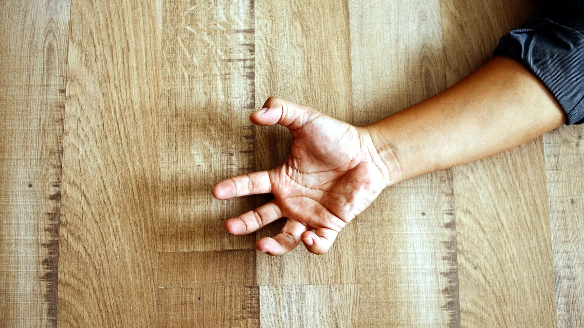 A hand resting flat on a smooth oak surface, fingers spread wide.