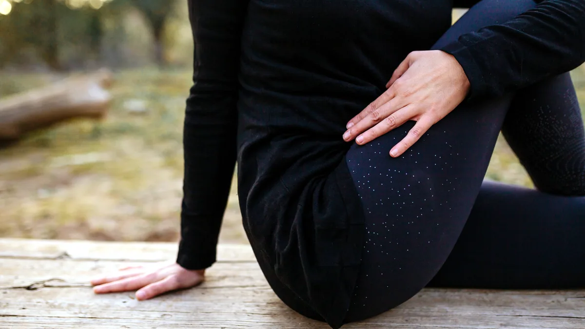 Hands resting on a knee as the leg extends in a slow stretch.