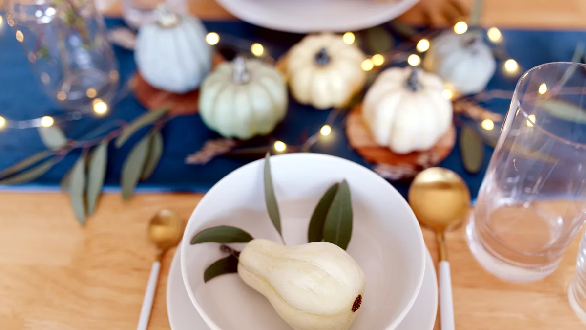 A set dining table with a low centerpiece of roses and eucalyptus.